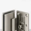 Bisagra de puerta de ducha de vidrio sin marco de níquel cepillado sobre una superficie de estudio gris claro