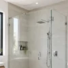 Cerramiento de ducha de vidrio sin marco fijado con abrazaderas de cromo pulido en un baño brillante con azulejos