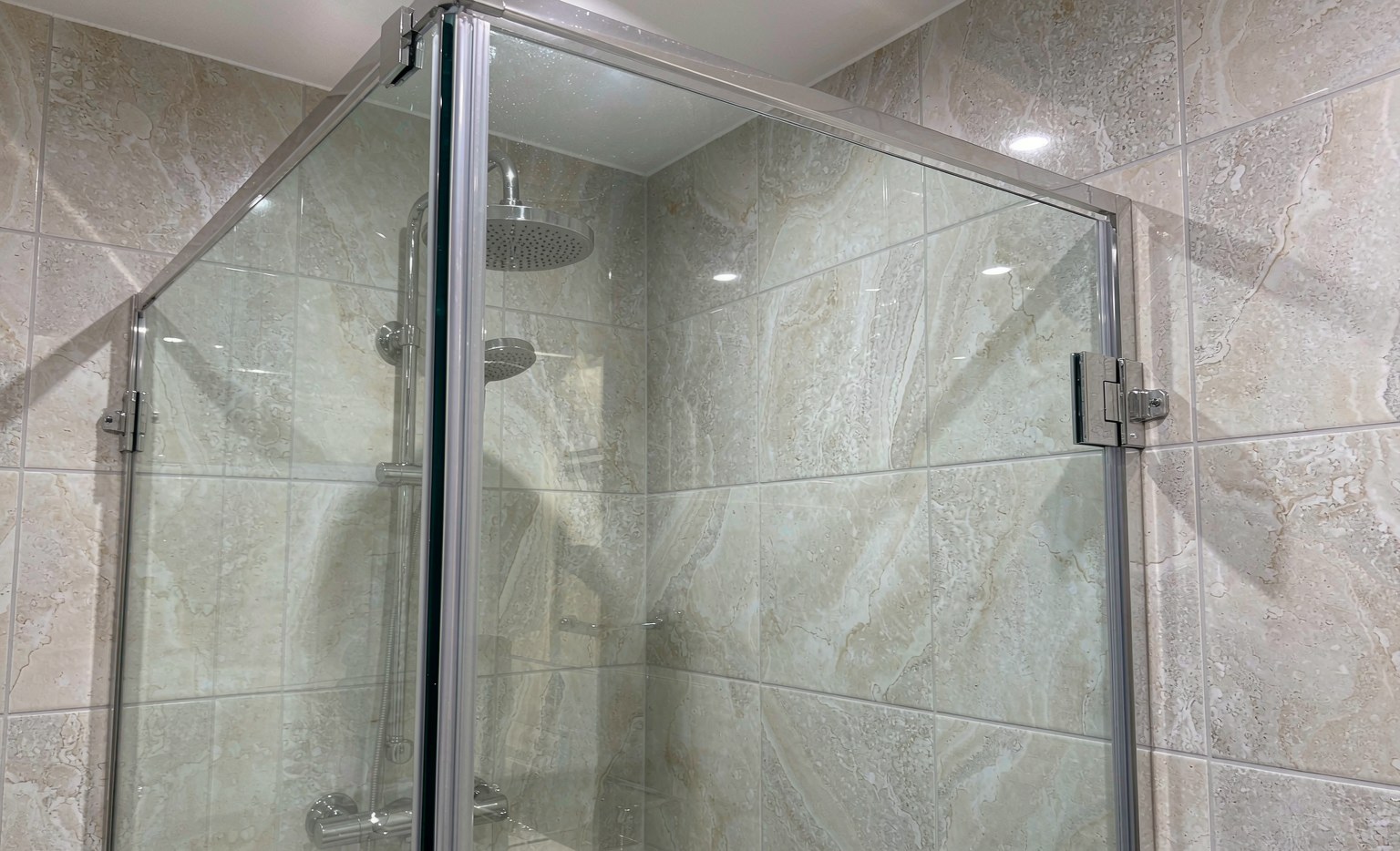 Frameless shower door in tempered glass on a tiled wall