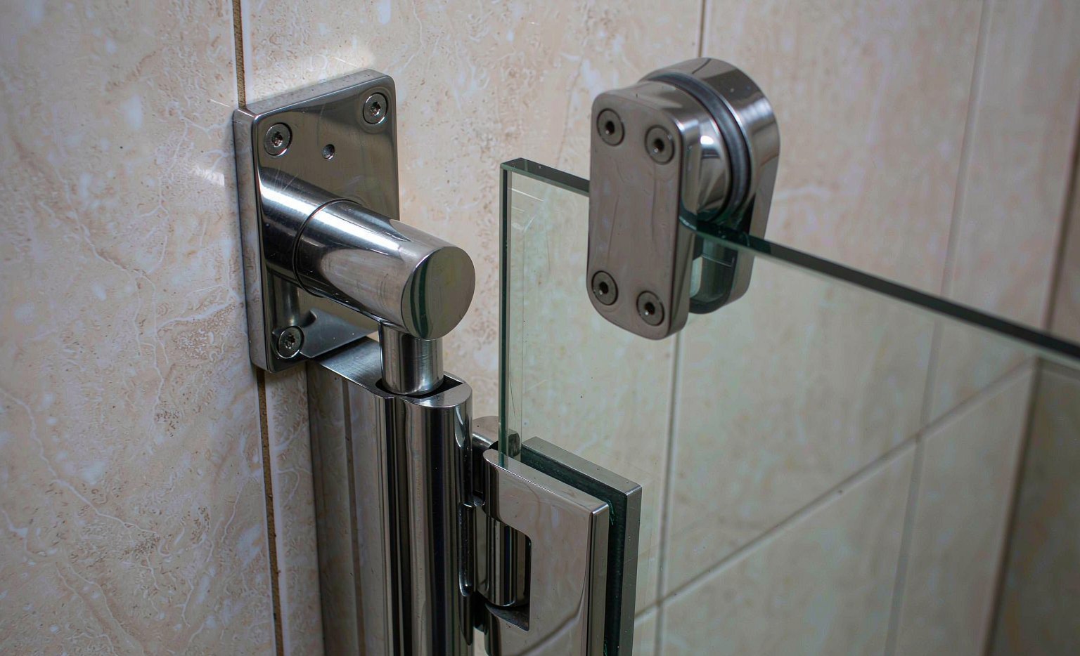 Stainless steel glass clamps fixing a frameless shower panel to the wall