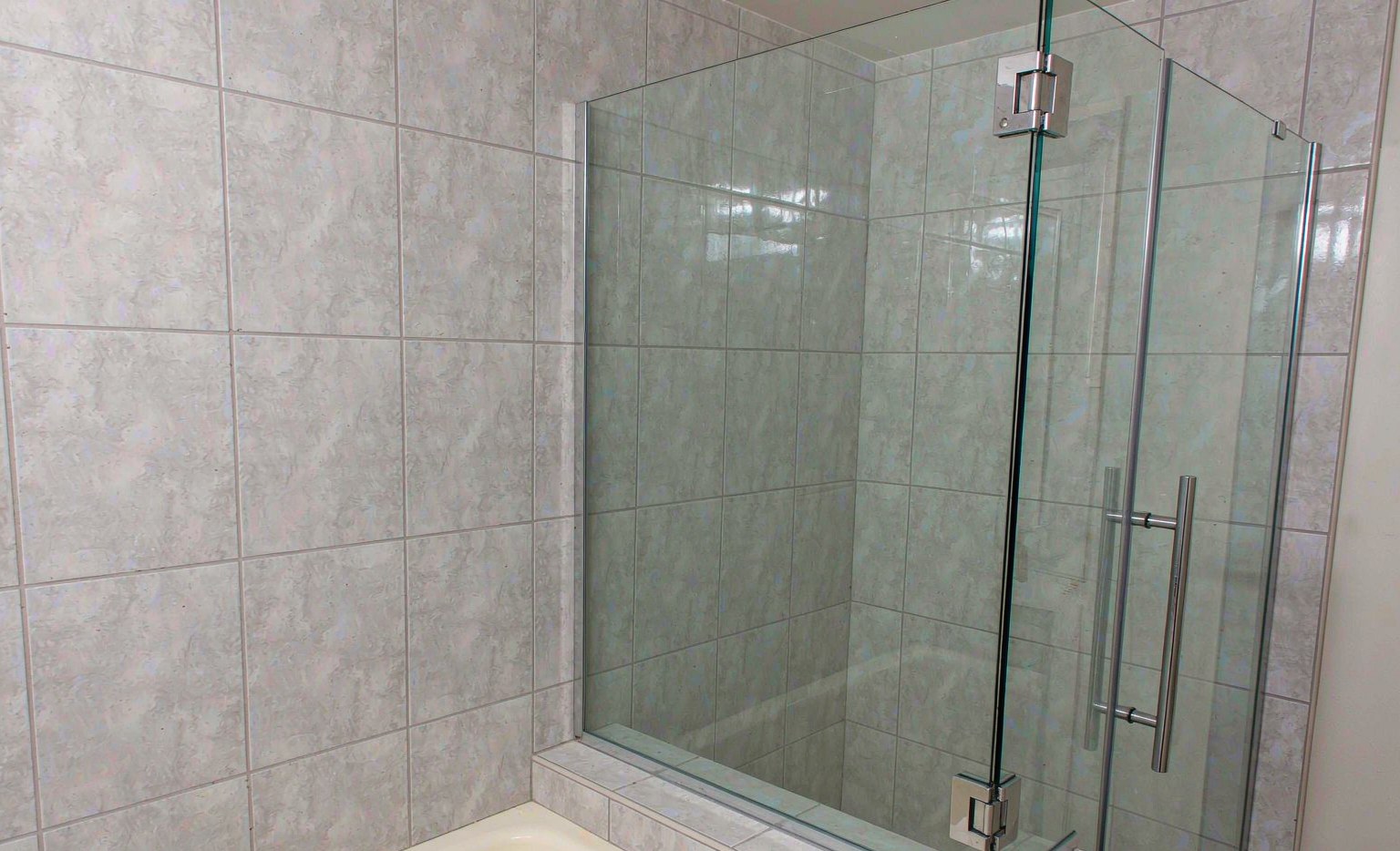 Frameless walk-in shower enclosure with glass-to-glass hinge fittings