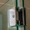 Chrome stainless steel glass shower door hinge mounted on a tempered glass panel in a frameless enclosure