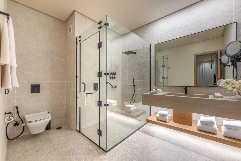 Zimmor 9000 Series heavy-duty shower hinge installed on a frameless glass shower door in a modern bathroom