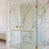 Modern frameless glass shower enclosure with brushed gold hinges and handles