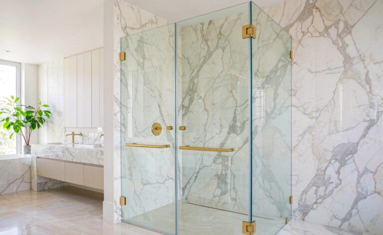 Modern frameless glass shower enclosure with brushed gold hinges and handles