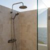 Outdoor coastal shower enclosure with metal hardware exposed to sea air