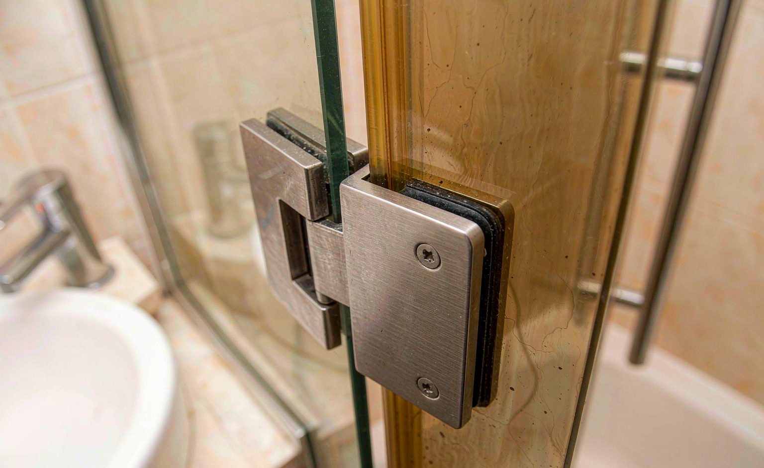 Macro of a frameless shower glass clamp hinge gripping thick tempered glass