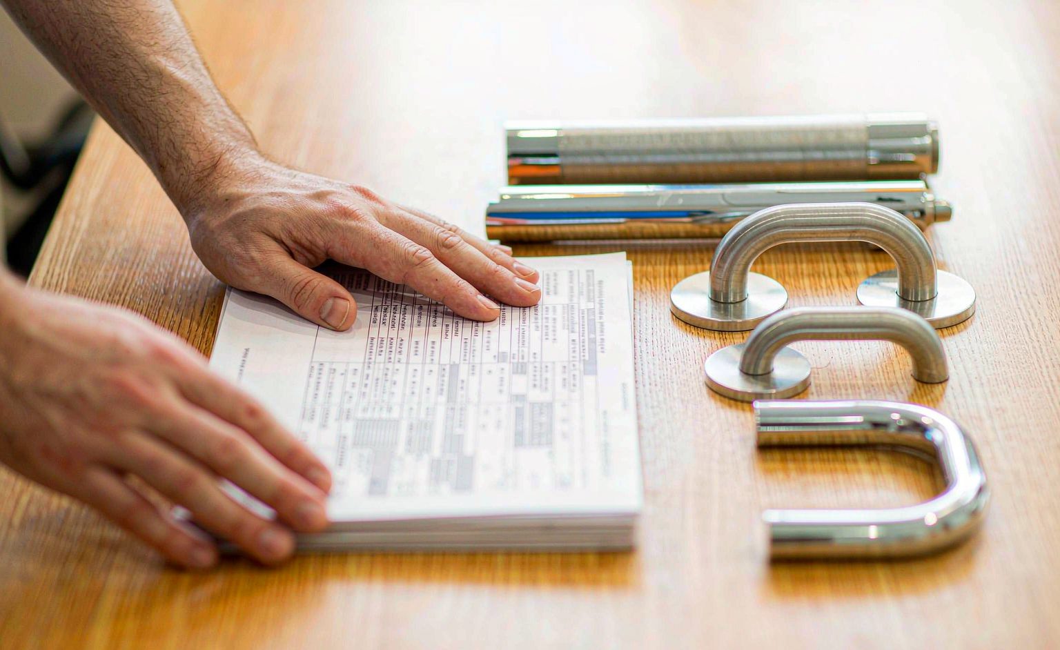 Buyer reviewing a printed quotation beside shower hardware samples on a desk